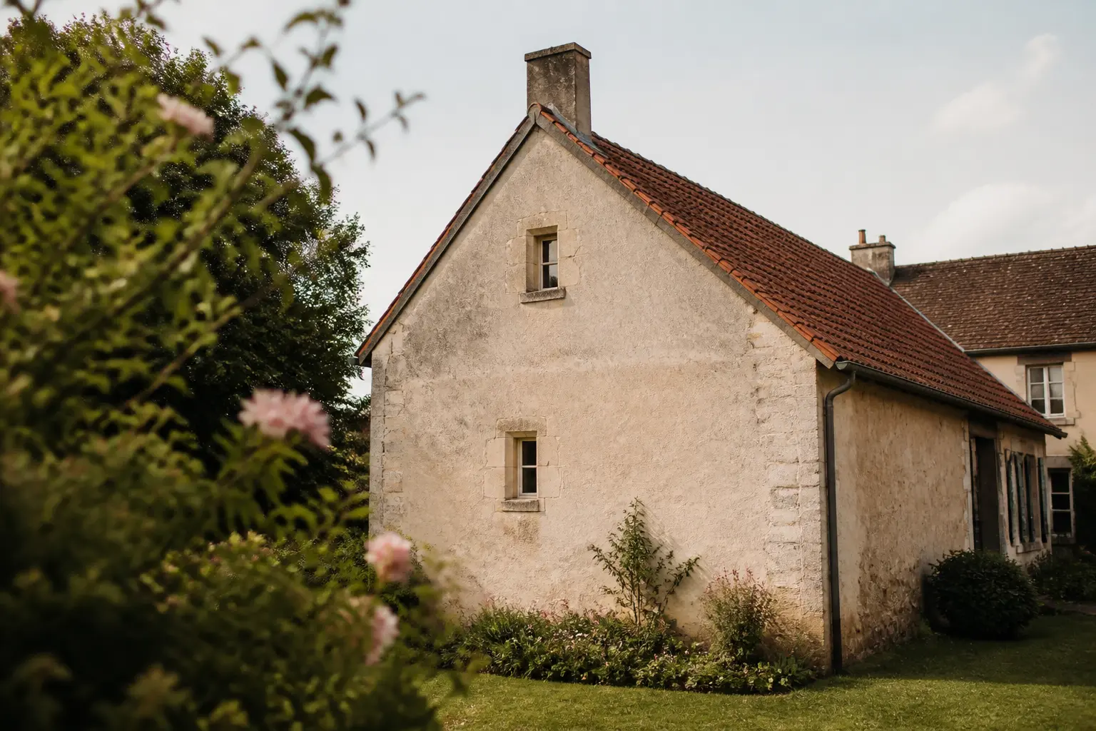 Pignon maison d’une habitation française, façade vieillie, fissures fines et traces d’humidité sous toiture inclinée