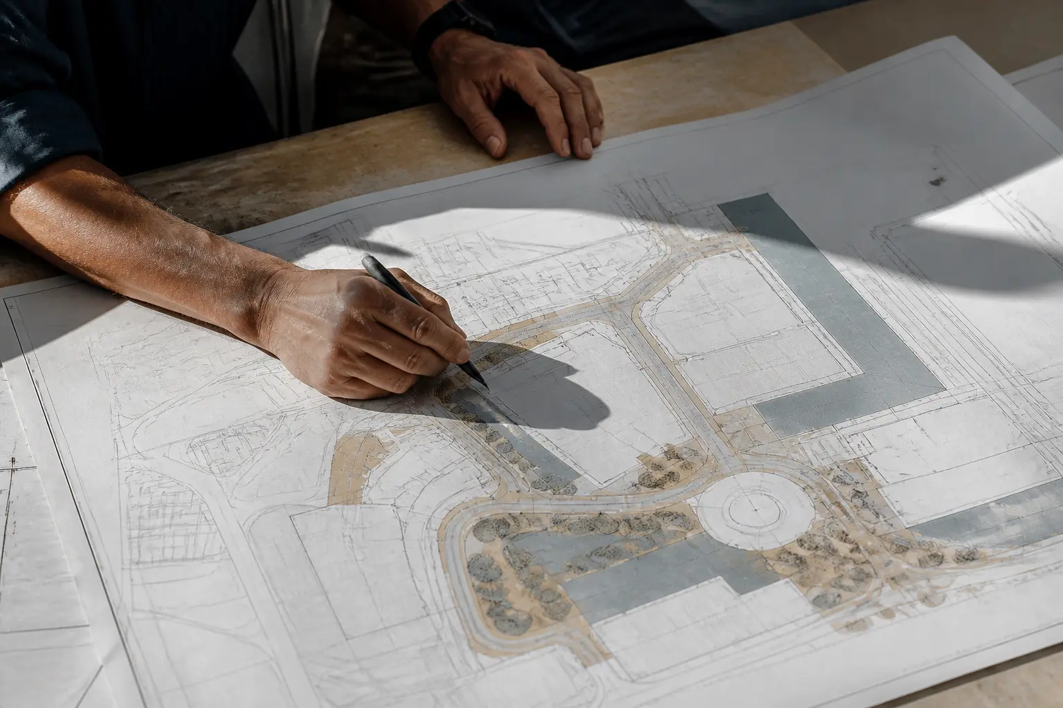 Exemple de plan de masse sur table de bureau d’urbanisme, vue plongeante sur plan architectural éclairé par une lumière dure.