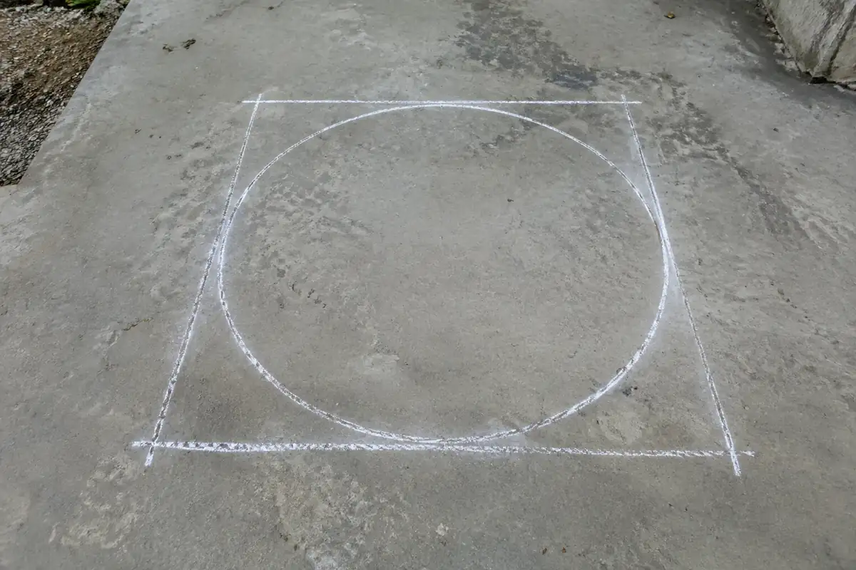 Cercle tracé à la craie sur une dalle de béton avec un carré autour